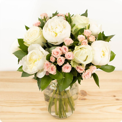 Ce bouquet raffiné est composé de pivoines et de roses dans des teintes roses et blanches